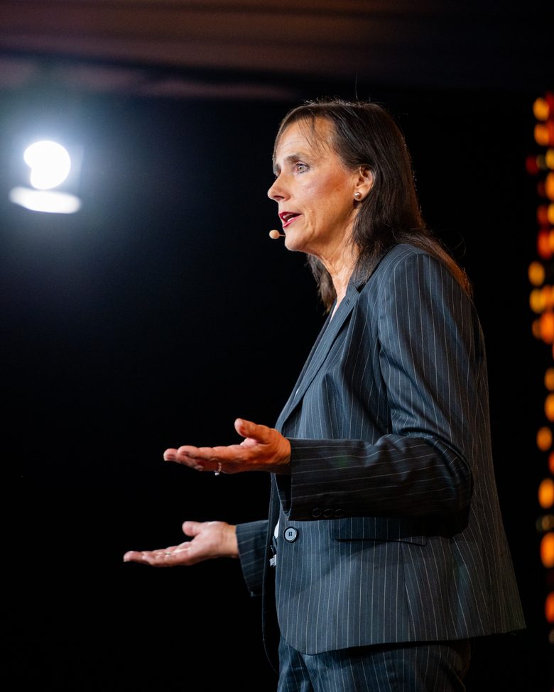 Claudia Christine Siegel im Vortrag, mit Headset-Mikrofon und offener Geste